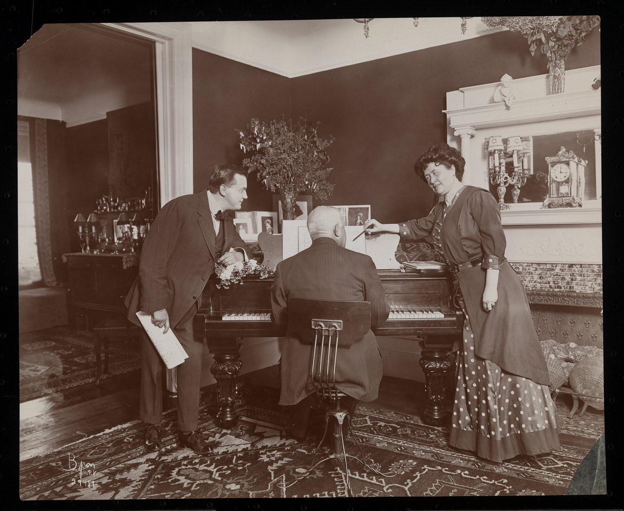 Clara De Regand egy kottára mutat, miközben egy férfi zongorázik, 1910 (ezüstzselatinos nyomat) alkotó: Byron Company