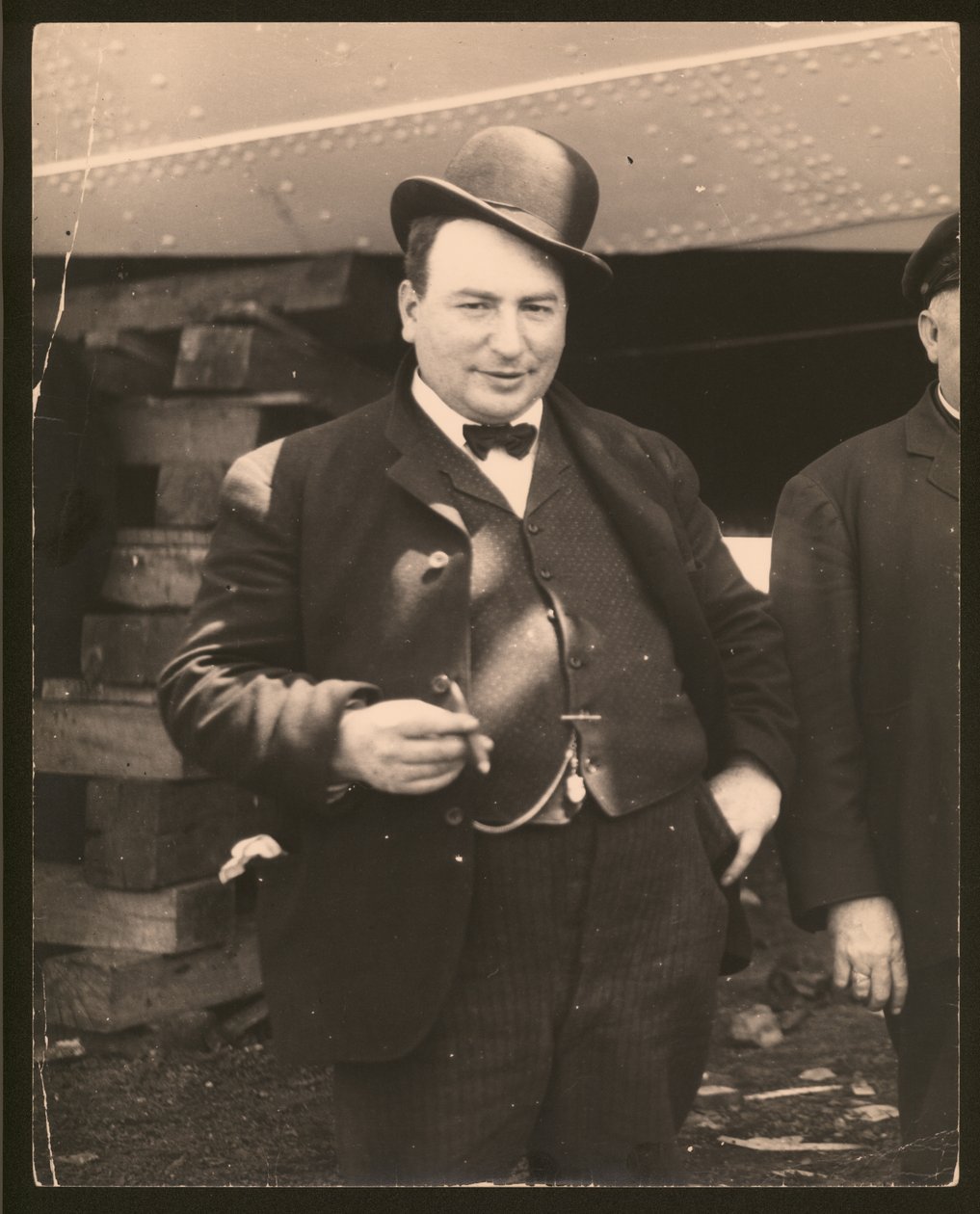 Függőleges, fekete -fehér fénykép derbi sapkában és csokornyakkendőben, szivarozva alkotó: William G. Swekosky